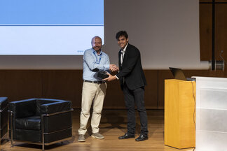 One person handing over an award to another on stage