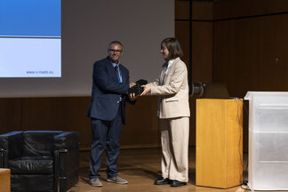 One person handing over an award to another on stage